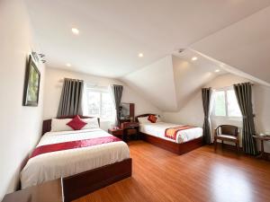 1 dormitorio con 2 camas, mesa y sillas en White Horse Dalat Hotel en Dalat