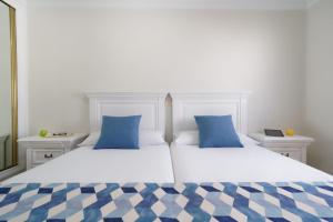 two white beds with blue pillows in a bedroom at Labranda Los Cocoteros in Puerto del Carmen