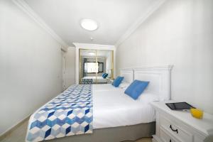 1 dormitorio con 1 cama blanca grande con almohadas azules en Labranda Los Cocoteros, en Puerto del Carmen