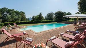 una piscina con sillas y sombrilla en Cosciano 12, Emma Villas, en Pomarance