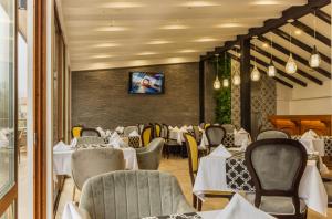 a restaurant with tables and chairs and a tv on a wall at Vemara City Apart Hotel in Varna City