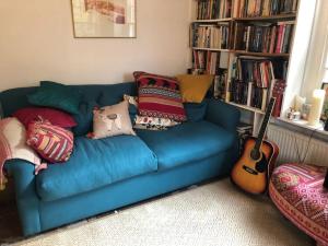 a blue couch with pillows and a guitar in a room at Bell Hay House in Glastonbury