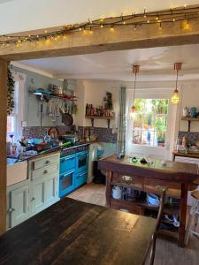 uma cozinha com armários azuis e uma mesa de madeira em Bell Hay House em Glastonbury