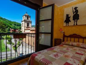 Un dormitorio con una cama y una ventana con una torre de reloj. en La Posta del Camín Real, en La Plaza