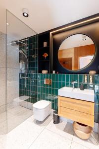 een badkamer met een toilet, een wastafel en een spiegel bij Penthouse Stradom by LoftAffair in Krakau