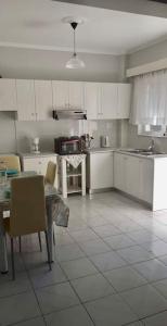 a kitchen with white cabinets and a table and a table and chairs at Handra Apartment Seaview in Kos Town