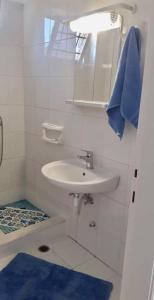 a white bathroom with a sink and a blue towel at Handra Apartment Seaview in Kos Town