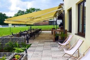 un patio con mesas y sillas bajo una sombrilla amarilla en Hotel ROSE Břeclav en Břeclav