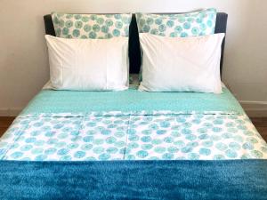 1 cama con 2 almohadas y edredón azul en Les oliviers en Rolle