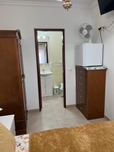 ナザレにあるMoradia da Ilda - Casas de Férias Nazaréのベッドルーム(冷蔵庫、ドレッサー付)、バスルームが備わります。