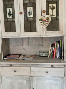 a white cabinet with a shelf with books at Domek Masuria in Orzysz