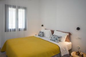 a bedroom with a bed with a yellow blanket and pillows at Alko Apartments in Mýkonos City
