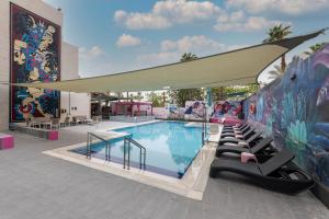 a swimming pool with lounge chairs next to a mural at Abraham Eilat in Eilat