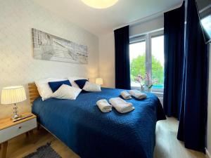a bedroom with a blue bed with two pillows on it at Klif Apartamenty Nadmorskie Tarasy in Kołobrzeg