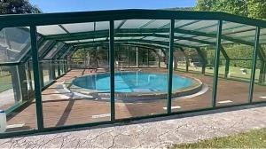 una piscina bajo un pabellón de metal con bañera de hidromasaje en casa rústica, en Olot