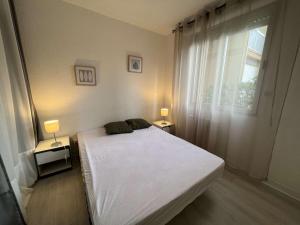 1 dormitorio con cama blanca y ventana en Appartement Valras-Plage, 2 pièces, 4 personnes - FR-1-701-68, en Valras-Plage