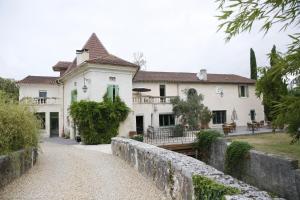 a large white house with a stone wall at Le Moulin de Saint-Aulaye in Saint-Aulaye