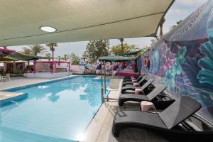 een zwembad met ligstoelen naast een muur bij Abraham Eilat in Eilat +37 foto's