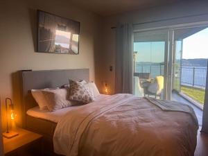 a bedroom with a bed with a view of a balcony at Sjøutsikt, jacuzzi og solfylt in Bergen +47 photos