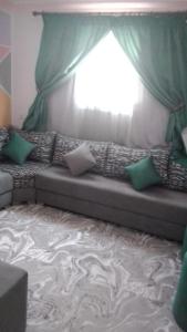 Sofá con almohadas en una habitación con ventana en appartement pour famille en Agadir