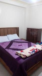 a bed with a purple blanket on top of it at appartement pour famille in Agadir