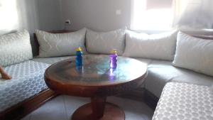 a living room with a couch and a table with two bottles on it at appartement pour famille in Agadir