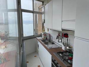 eine Küche mit weißen Schränken, einem Waschbecken und einem Fenster in der Unterkunft Panoramico a Posillipo in Neapel