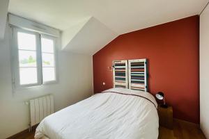 een slaapkamer met een wit bed en een rode muur bij Spacious house with garden in La Rochelle