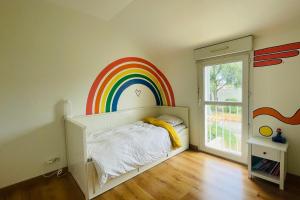 een slaapkamer met een regenboog muurschildering aan de muur bij Spacious house with garden in La Rochelle