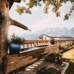 a wooden bench with plants on it with mountains in the background at Posers Bergwelt B&B in Schladming