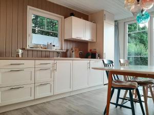 een keuken met witte kasten en een tafel met stoelen bij Annemarie Zerpenschleuse - Schwedenhaus mit Künstler-Charme und Sauna in Zerpenschleuse