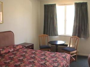 a bedroom with a bed, chair, desk and a lamp at Hometown Inn Galion in Galion