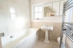 Baño blanco con lavabo, bañera y espejo en Stunning Flat in Highbury Hill, en Londres