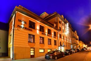 un bâtiment avec des voitures garées dans une rue la nuit dans l'établissement Hotel Panorama Nowy Sącz, à Nowy Sącz