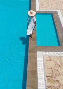 a person wearing a hat standing next to a swimming pool at Oceanides Luxury Apartments in Sitia