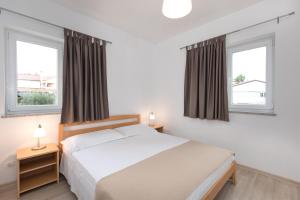 ein Schlafzimmer mit einem Bett und zwei Fenstern in der Unterkunft Apartmani LAURA Krk in Krk