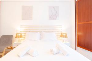 een witte slaapkamer met een wit bed en 2 lampen bij Apartamento Cimadevilla II in Gijón