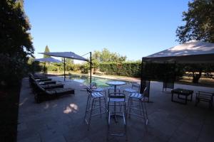 eine Terrasse mit Tischen, Sonnenschirmen und einem Pool in der Unterkunft Magnifique Gîte en provence in Sarrians