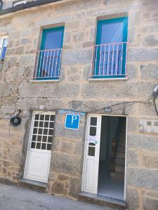 un edificio de piedra con 2 ventanas y una puerta en pension mar de rosa, en Villanueva de Arosa