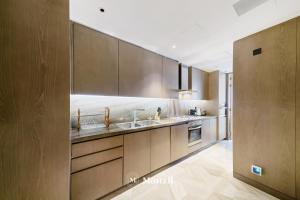 a kitchen with wooden cabinets and a sink at Manzil - Lavish 2BR Sea View Apartment in Five Palm, Palm Jumeirah in Dubai