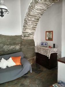 Unique traditional house dating from 1700 في Kástron: غرفة معيشة مع أريكة وجدار حجري