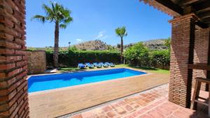 a swimming pool in a yard with palm trees at CASA PEPE Y MARI CON PISCINA in Alora +12 photos