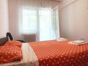 an orange bed with polka dot sheets and a window at Apartament Herculane cu vedere la munte in Băile Herculane
