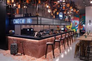 a restaurant with a bar with a bunch of stools at Moxy Athens City in Athens