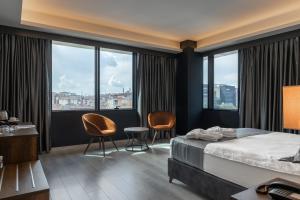 um quarto de hotel com uma cama, cadeiras e janelas em The Plaza Hotel Edirne em Edirne