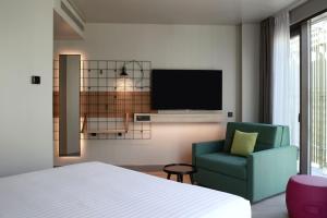 een slaapkamer met een bed en een stoel en een tv bij Moxy Athens City in Athene