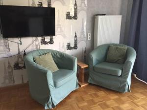 Duas cadeiras e uma televisão de ecrã plano numa sala de estar em Haus Magnolia 1 em Kandern