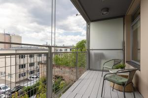 balkon z krzesłem i widokiem na budynek w obiekcie Royal Park Łazienki Apartment Warsaw Mokotów by Renters w Warszawie
