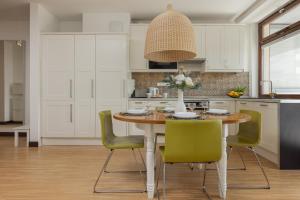 a kitchen with a wooden table and green chairs at Royal Park Łazienki Apartment Warsaw Mokotów by Renters in Warsaw