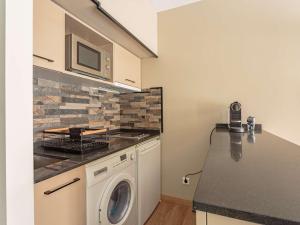eine Küche mit einer Waschmaschine und einer Mikrowelle in der Unterkunft Studio Hendaye, 1 pièce, 4 personnes - FR-1-2-431 in Hendaye